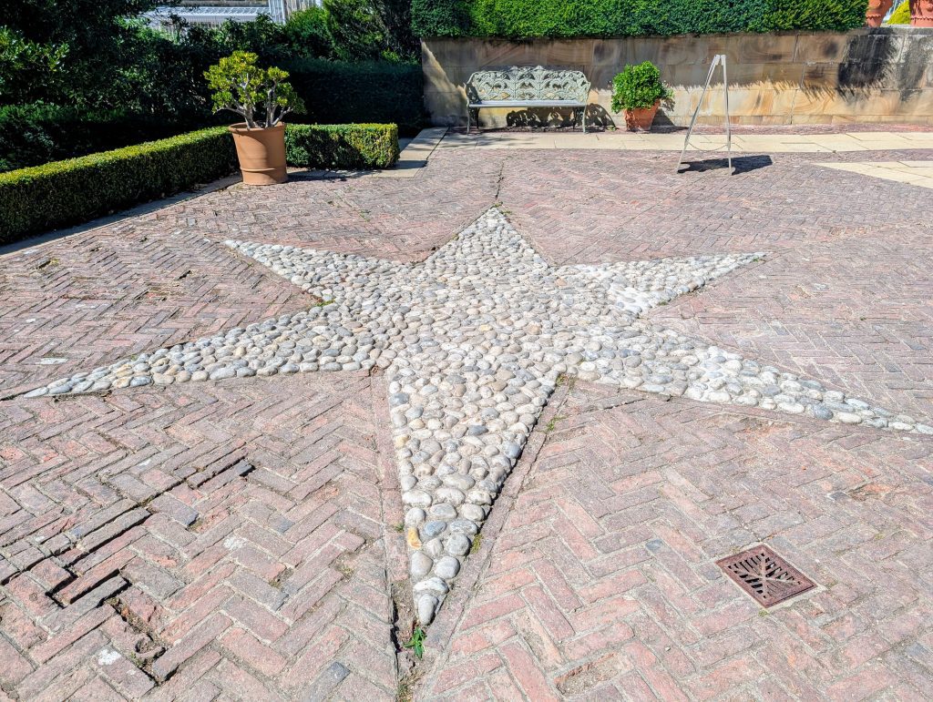 A star made up of different coloured pebbles on a patio