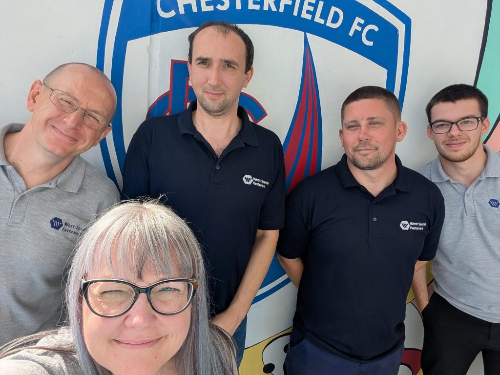 West colleagues stood in front of the badge at Chesterfield Football club