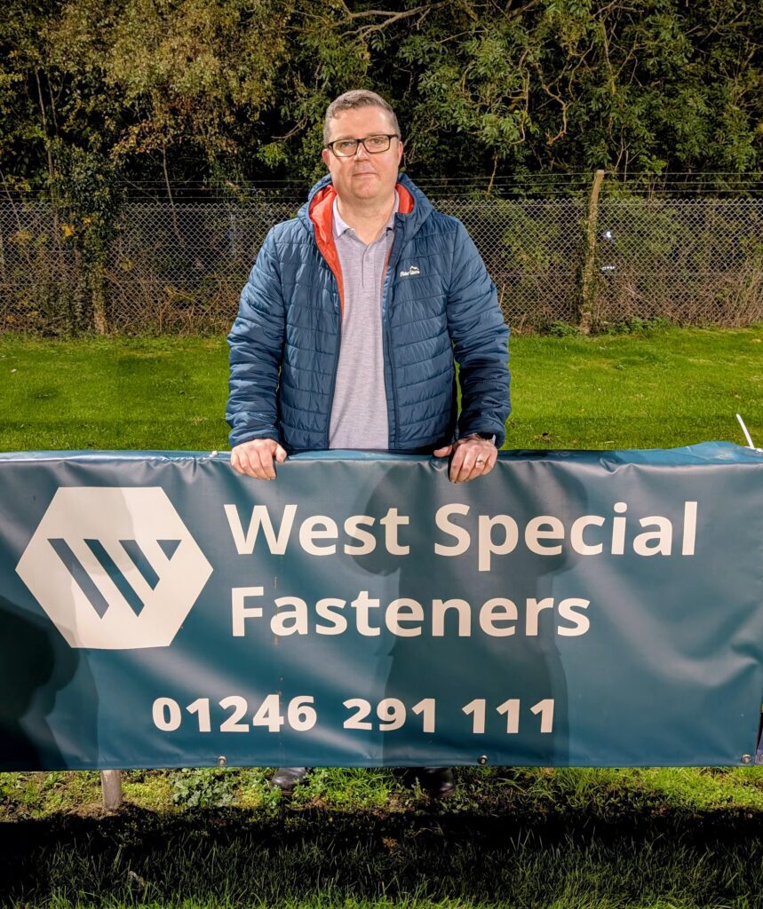 A man stands behind the West Special Fasteners advertising board